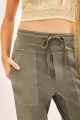 Pantalón tipo babucha de gabardina elastizada, color negro, con cintura elástica ajustable mediante cordón, puños en los tobillos, bolsillos diagonales frontales y bolsillos traseros con solapa y botón.
