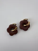 Aros de acero quirúrgico dorados con dijes en forma de flor de color marrón.