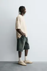 Camiseta color caqui de corte holgado, con cuello redondo y mangas cortas. Acabado con efecto lavado y ruedo irregular.