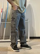 Jean baggy cargo color gris gastado, con tiro alto, piernas anchas y múltiples bolsillos laterales funcionales.