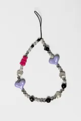 Correa para celular decorativa con cuentas multicolores, dijes de corazones lilas, oso fucsia, cuentas en forma de concha plateadas y dados negros.