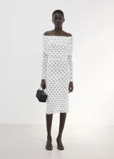 Vestido midi entallado de color blanco con estampado de lunares negros, escote palabra de honor con solapa drapeada y manga larga.