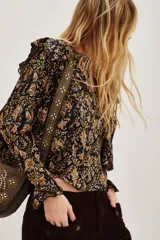 Camisa de manga larga con estampado paisley en tonos negros, amarillos y rosados. Presenta volados en los hombros, puños con terminación en volado y cierre frontal con botones.