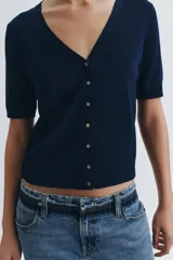 Chaqueta de punto azul marino confeccionada en lana extrafina, con cuello en V, manga corta y cierre frontal con botones.