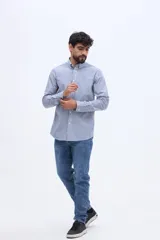 Camisa de manga larga con diseño de rayas verticales blancas y azules, corte regular, cuello camisero abotonado y un bolsillo aplicado en el pecho.