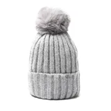 Gorro de lana gris con textura acanalada y pompón en la parte superior.
