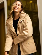 Campera color beige de poliéster, marca Michael Kors. Tiene cierre central oculto con botones a presión, bolsillos delanteros, capucha escondida en el cuello y avíos metálicos dorados con logo.