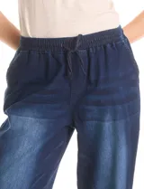 Pantalón tipo jogger de denim azul con efecto lavado. Presenta cintura elástica con cordón ajustable, bolsillos laterales y traseros, y puños elásticos en los tobillos.