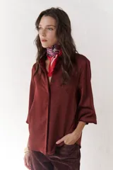 Camisa azul marino de satén con cuello clásico, cierre frontal con botones y mangas largas con puños abotonados.