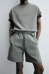 Bermuda de algodón color beige claro, corte relajado (relaxed fit), con cintura elástica ajustable mediante cordón y bolsillos laterales y trasero de plastrón.