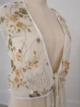Top halter de color beige con diseño cruzado al frente, escote pronunciado y detalles de bordado con lentejuelas y cuentas doradas.