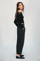 Pantalón de tiro medio con corte tipo ballon, bolsillos delanteros y detalle de pinzas. Cuenta con cierre frontal de cremallera y gancho metálico.