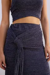 Falda larga de tejido brillante color azul con detalle de nudo en la cintura.