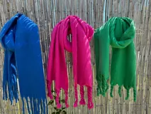 Bufanda larga de tejido suave, disponible en azul, fucsia y verde.