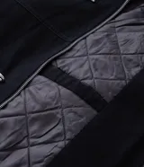 Campera de sarga de algodón con capucha, cierre frontal con cremallera y trabas metálicas decorativas. Presenta un bolsillo con cierre en la manga y puños elásticos, con un diseño de estilo utilitario.
