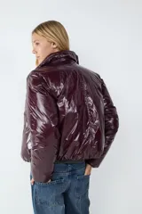 Campera puffer de corte recto con acabado brillante efecto gloss, cierre frontal completo y cuello clásico.