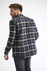 Sobrecamisa de viyela para hombre con estampado de cuadros en rojo y negro. Presenta cierre frontal con botones, bolsillos en el pecho con solapa y botón, y un interior capitoneado para mayor abrigo. Cuenta con un logo en grifa de cuero.