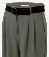 Pantalón de sastrería modelo wide leg color verde militar, confeccionado en crepé. Presenta pliegues delanteros, cintura con trabillas e incluye un cinturón de gamuza a tono.