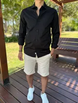 Camisa clásica negra de manga larga con botones frontales y cuello camisero.