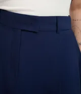 Short pollera azul marino de sastrería, confeccionado en mezcla de viscosa y poliéster, con pliegues frontales, cintura fija con presillas y cierre frontal con cremallera y gancho.