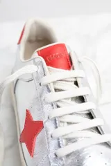 Zapatillas plateadas de cuero metalizado con estrella roja en el lateral y detalles en rojo en el talón.