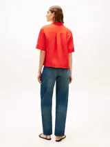 Camisa de manga corta de corte amplio color rojo, confeccionada en puro lino. Cuenta con cuello inglés, bolsillo de parche en el pecho con logo bordado y hombros ligeramente caídos.