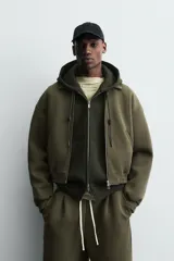 Cazadora de corte boxy fit confeccionada en tejido técnico compacto de algodón con elasticidad. Presenta cuello solapa, cierre frontal con cremallera, bolsillos de vivo en la cadera y acabados elásticos en puños y bajo.