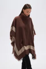 Poncho de tejido grueso, color negro y gris, con diseño de franjas diagonales y cuello alto con cierre. Presenta terminaciones con flecos.