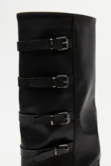 Bota de caña alta estilo biker, color negro, con plataforma robusta y suela dentada. Presenta múltiples tiras laterales con hebillas metálicas ajustables.