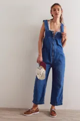 Enterito de denim azul con calce relajado, escote cuadrado, cierre frontal y diseño tipo jardunera con bolsillos.