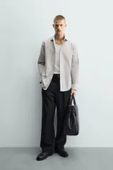 Camisa de corte slim fit confeccionada en tejido de algodón, con estampado de cuadros pequeños en tonos beige y blanco. Presenta cuello italiano, manga larga con puños abotonados y cierre frontal con botones.