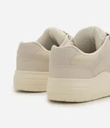 Championes estilo skate de poliuretano color beige, con suela voluminosa, recortes en la capellada y cordones gruesos bicolores.