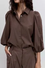 Pantalon de vestir color marron, de corte sastrero con piernas anchas y tiro alto. Presenta pinzas frontales y bolsillos laterales.