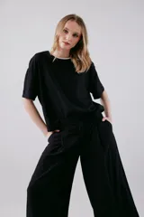 Blusa color beige de viscosa texturizada, con cuello redondo con detalle de sesgo a contratono negro, espalda con escote gota y lazo.