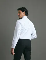 Camisa de vestir blanca de manga larga, con cuello clásico, cierre frontal de botones y bolsillo en el pecho.