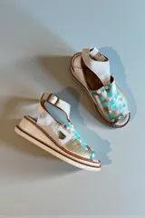 Sandalias de cuero de suela semiplataforma y taco de 4 cm, con diseño frontal pintado a mano en tonos turquesa, marrón y dorado. Cuentan con tira al tobillo con hebilla metálica y detalle de aplique con logo.