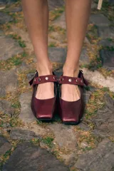 Ballerinas de cuero bordó con puntera cuadrada, diseño destalonado y tira en el empeine decorada con tachas metálicas.