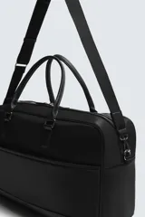 Bolso de viaje negro de tejido técnico, con compartimento principal con cierre de cremallera, bolsillo interior con cremallera y bolsillo frontal plano. Cuenta con dos asas de mano y una correa de hombro ajustable y extraíble.