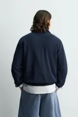 Sudadera regular fit azul marino confeccionada en tejido de algodón con estructura piqué. Cuenta con cuello subido, cierre frontal de cremallera corta y mangas largas con acabados en rib.