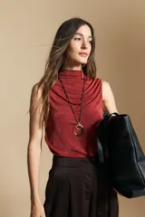 Top sin mangas de cuello alto con diseño drapeado en el frente, confeccionado en tela satinada de color bordó.