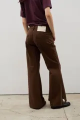 Pantalón de denim tiro alto con corte oxford y tajos laterales en el ruedo. Presenta cierre frontal con botones a la vista y costuras verticales decorativas.