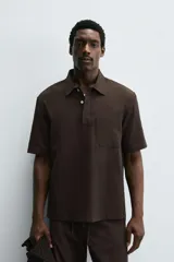 Camisa tipo polo de corte relajado confeccionada en una mezcla de lyocell y algodón. Presenta cuello con solapa, cierre frontal de botones ocultos, manga corta y un bolsillo de parche en el pecho. El bajo cuenta con aberturas laterales.