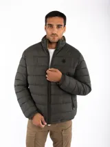 Campera puffer reversible color verde azulado con interior gris. Tiene cuello alto, cierre frontal y bolsillos laterales con cierre.