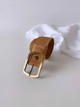 Cinto de cuero color camel con hebilla metálica rectangular plateada. Diseño clásico con sistema de broche para intercambiar hebillas.