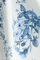 Vestido midi de popelina de algodón en color blanco con estampado floral azul, escote corazón y tirantes finos de lazo. Presenta cuerpo entallado, espalda elástica tipo nido de abeja y falda amplia con vuelo.