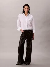 Pantalón negro de pierna ancha con efecto piel, talle medio y diseño clásico de cinco bolsillos, cierre de botón y cremallera.