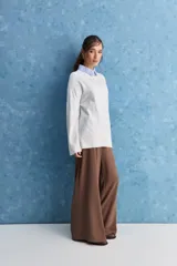 Sweater blanco de punto con diseño holgado, cuello redondo, mangas largas acampanadas y detalles de textura horizontal en el tejido.