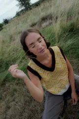 Chaleco de punto color amarillo y blanco con estampado geométrico, escote en V y ribetes marrones.