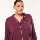 Conjunto de pijama de dos piezas color bordó, compuesto por una camisa de manga larga con cuello solapa, cierre frontal de botones y vivo en contraste, y un pantalón de corte recto y holgado con cintura elástica.