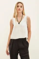 Top negro de poliéster con escote en V, tirantes con detalle de encaje y corte holgado.